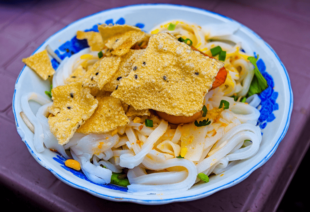Illustration of Shrimp and Pork Quang Noodles at Mi Quang Nhu, a hearty meal, even more delicious when eaten with quail eggs and crispy rice paper (Source: Canva)